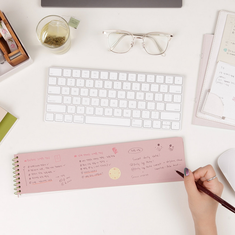 Eine Person vor einem Computer am Arbeitsplatz macht Notizen in ein Keyboard Memopad Strawberry.